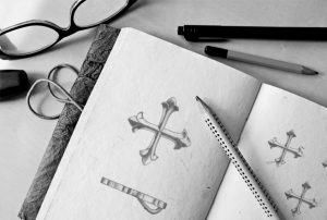 A sketchbook showing the design for a cross patonce charm.