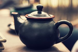 A black teapot with a red-rimmed top.