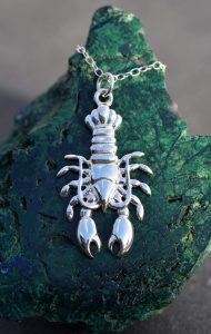 A sterling silver lobster pendant on a rock.