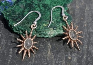 A pair of bronze sunburst earrings by Mallards with a blue stone centre