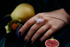 Silver bee pendant draped on a model's hand