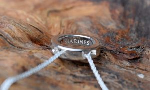 A circular silver Royal Marines pendant on wood
